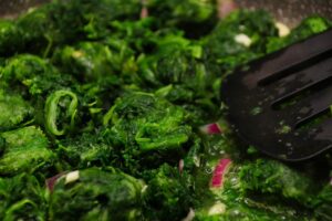 Spinaci cotti in padella, evidenziando l'importanza della corretta cottura per preservare il ferro.
